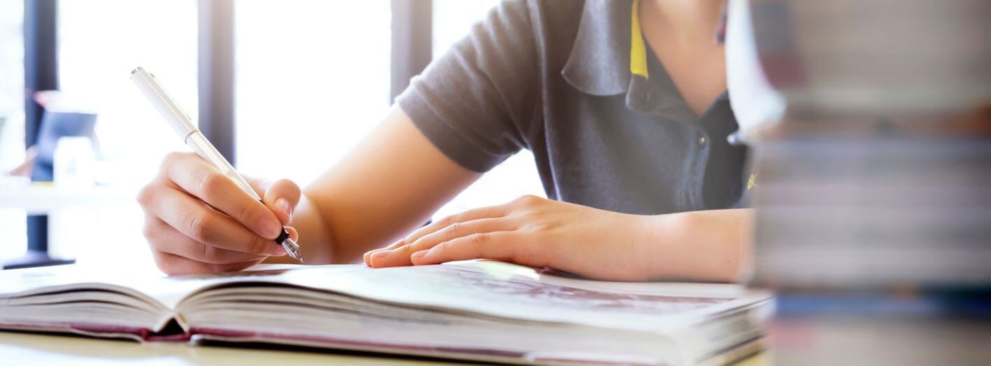 Joven estudiante escribiendo en un libro para conocer su identidad profesional